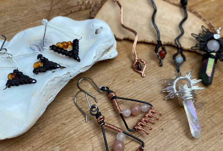 wooden table back ground with a selection of handmade wire wrapped jewellery with silver, copper and black wire