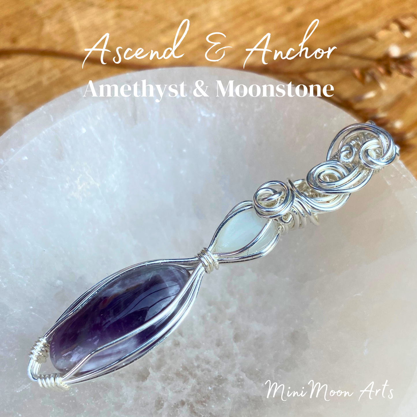 moonstone and amethyst wire wrapped silver wire pendant sat at an angle in a selenite bowl with a wooden table back ground