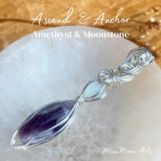 moonstone and amethyst wire wrapped silver wire pendant sat at an angle in a selenite bowl with a wooden table back ground