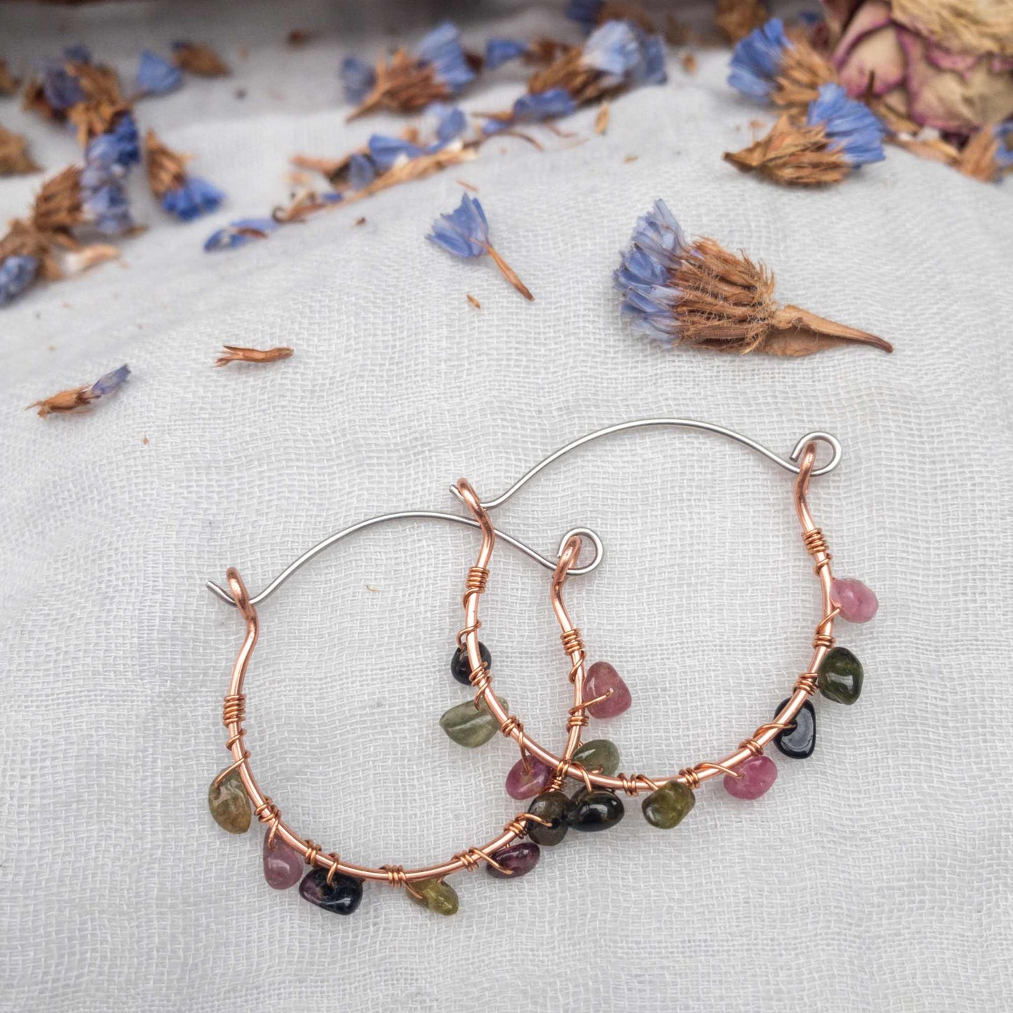 watermelon tourmaline wire wrapped handmade hoop earrings laid flat over lapping