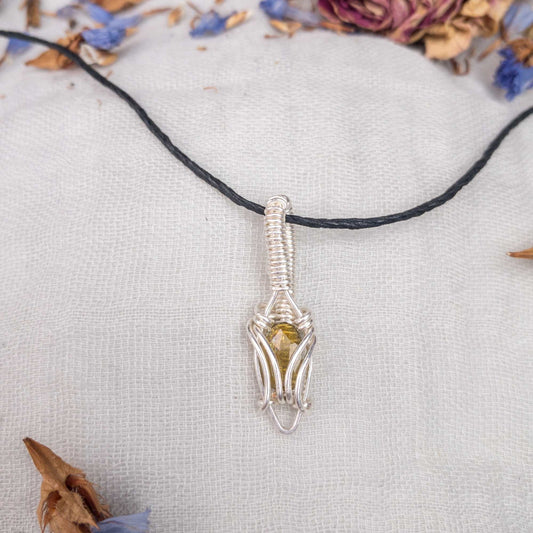 green tourmaline and silver filled wire dainty wire wrapped pendant displayed on hemp cord